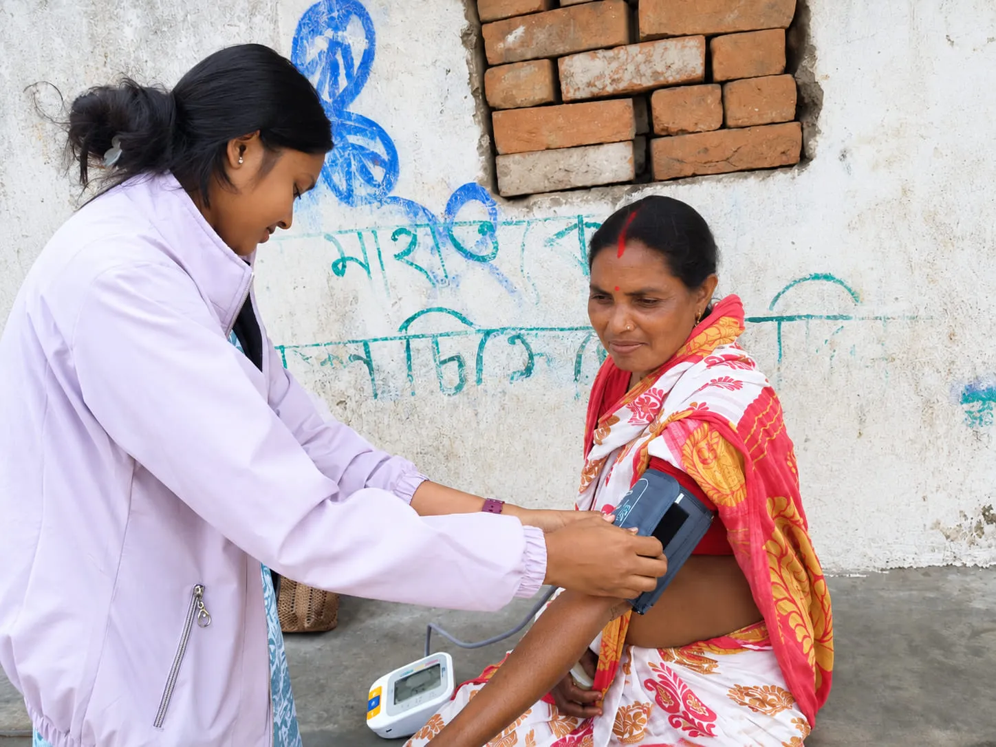 A health worker checking a villager’s blood pressure at a community session