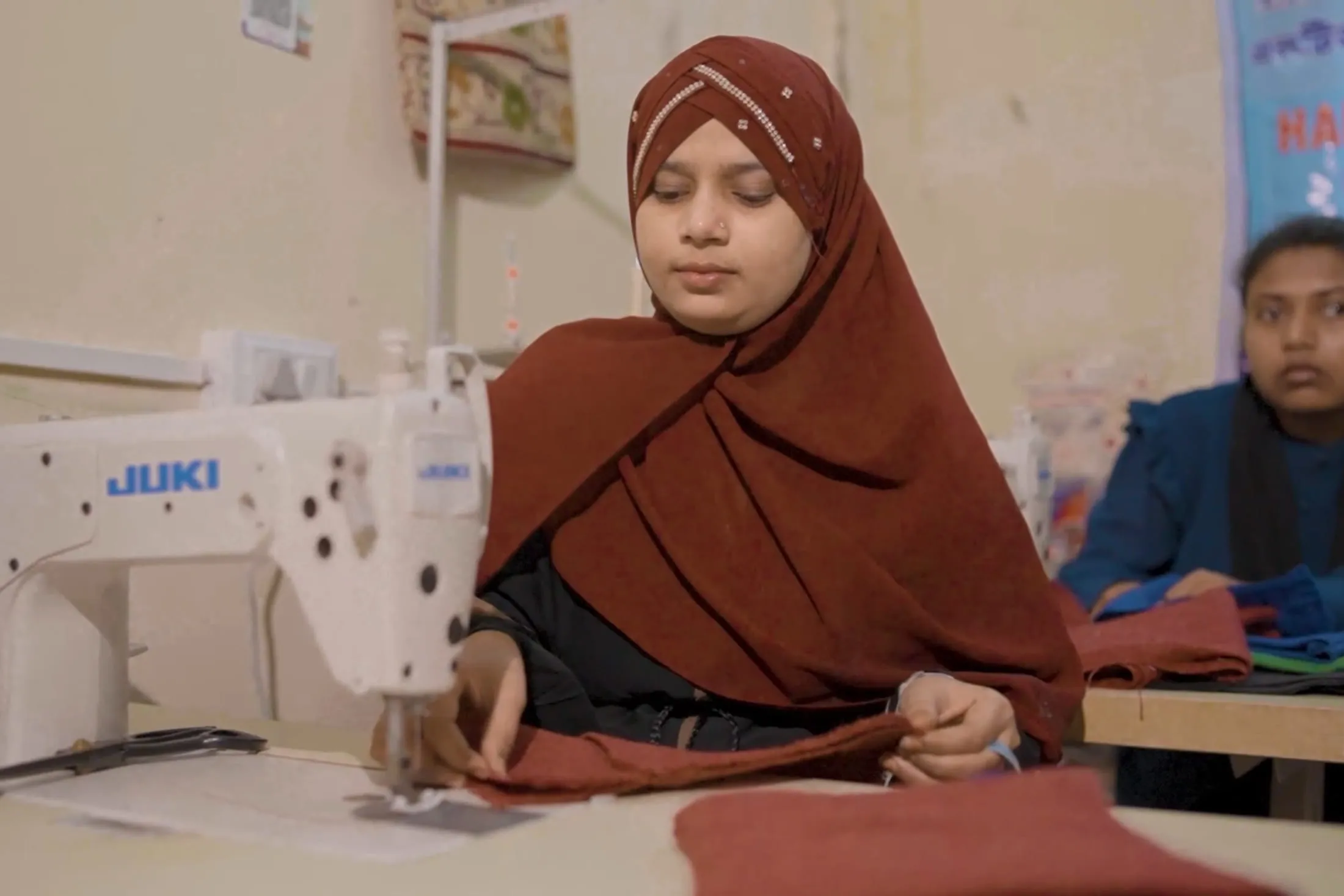 A trainee at work on an industrial sewing machine in the tailoring unit