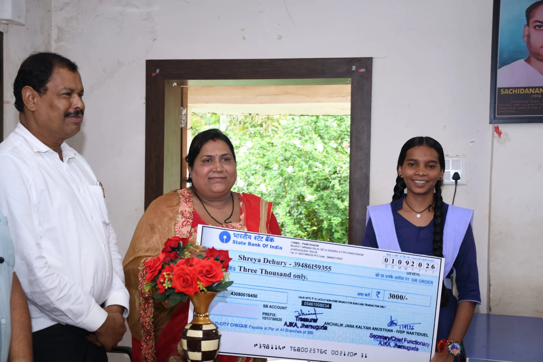 A student receiving a support cheque from AJKA staff at the project office