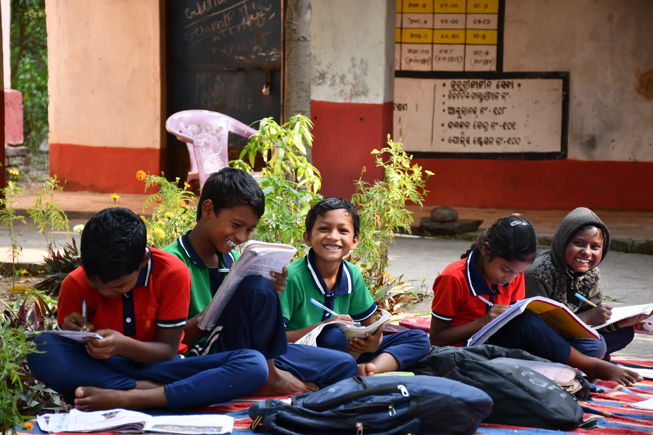Schoolchildren studying together on a mat in the open air